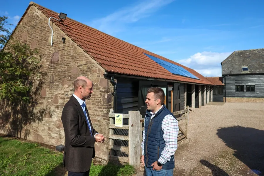 The Duke of Cornwall talks with Harry Davies beside a red-tiled stone barn in the yard at Monkhall Farm